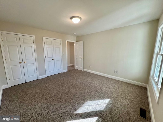 unfurnished bedroom featuring carpet floors and multiple closets