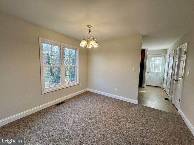 carpeted spare room featuring a chandelier