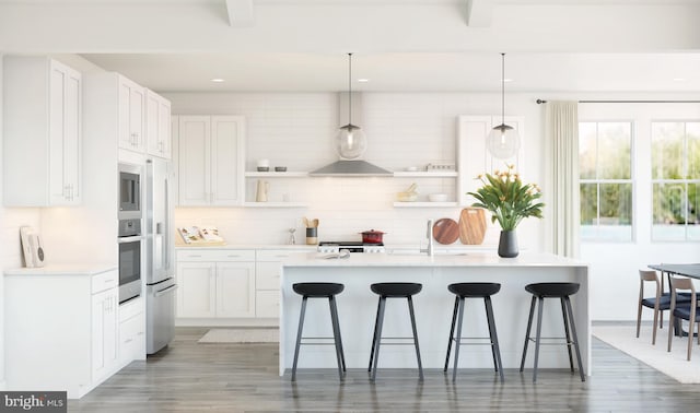 kitchen with white cabinets, decorative light fixtures, and a center island with sink