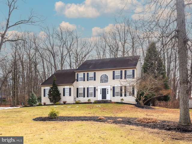 colonial-style house featuring a front lawn