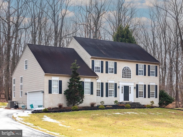 view of front of home with a garage, central AC unit, and a front lawn