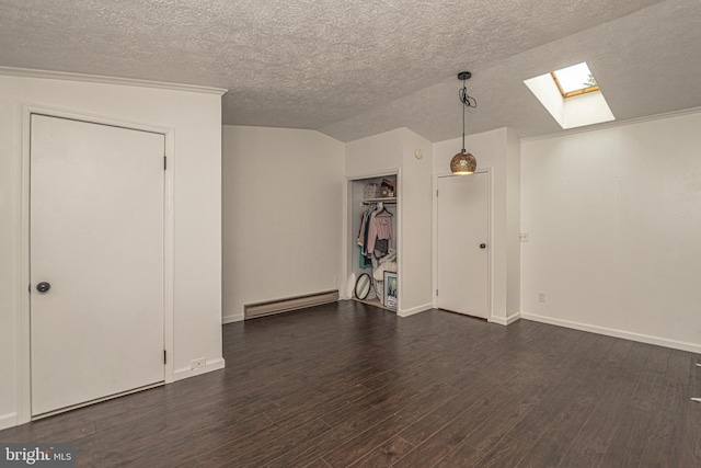 empty room featuring a textured ceiling, dark hardwood / wood-style flooring, lofted ceiling with skylight, and a baseboard heating unit