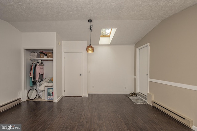 interior space with dark wood-type flooring, baseboard heating, lofted ceiling with skylight, a textured ceiling, and a closet