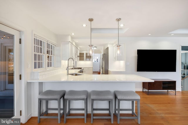 kitchen with sink, a kitchen breakfast bar, kitchen peninsula, stainless steel fridge, and pendant lighting