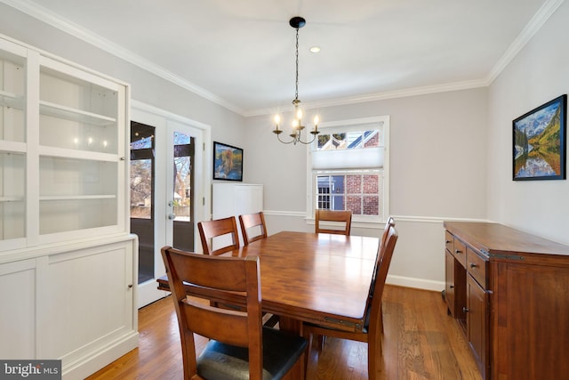 dining area with hardwood / wood-style flooring, an inviting chandelier, ornamental molding, and french doors