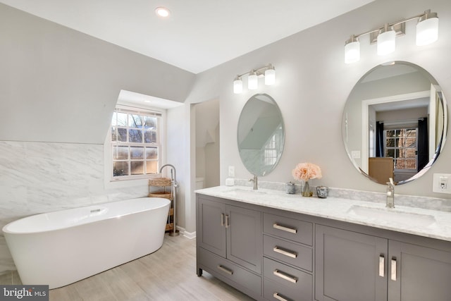 bathroom featuring a bath, vanity, tile walls, and hardwood / wood-style floors