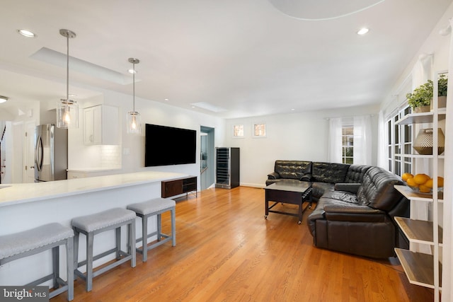 living room featuring a tray ceiling and light hardwood / wood-style flooring