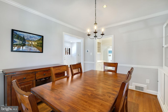 dining room featuring crown molding, a chandelier, and light wood-type flooring