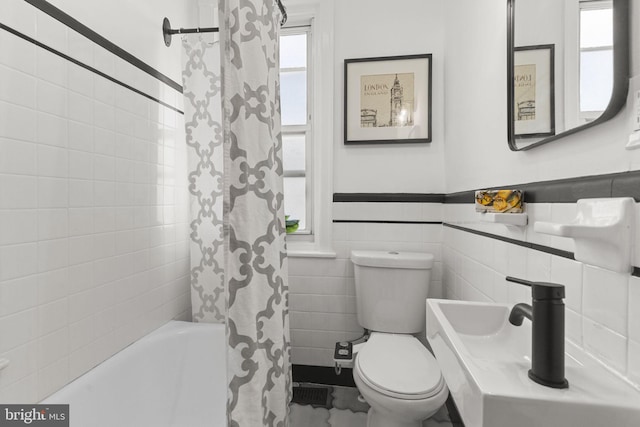 bathroom with shower / bathtub combination with curtain, toilet, and tile walls