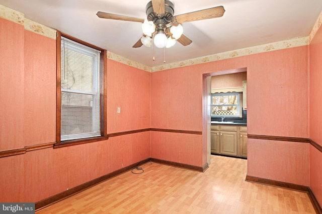 empty room with sink, ceiling fan, and light hardwood / wood-style flooring