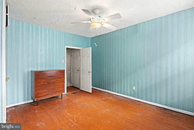 unfurnished bedroom featuring hardwood / wood-style flooring, ceiling fan, and a textured ceiling