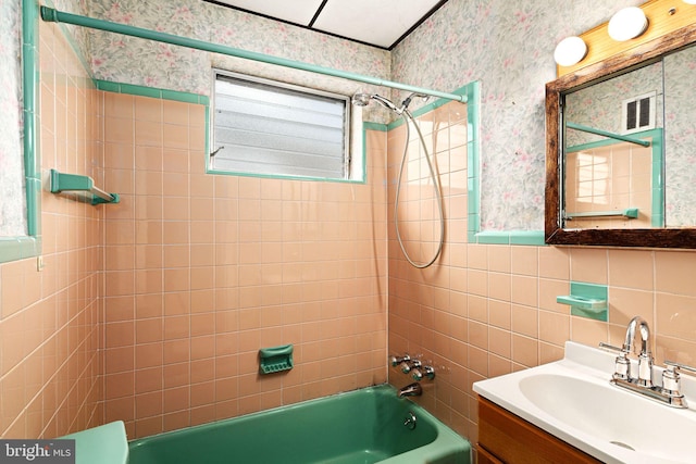 bathroom with tiled shower / bath, plenty of natural light, tile walls, and vanity