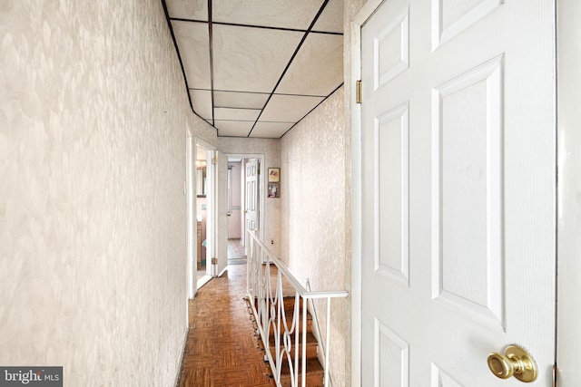 hallway featuring dark parquet flooring and a paneled ceiling