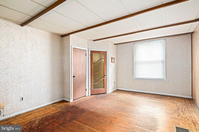 empty room featuring hardwood / wood-style flooring and a drop ceiling