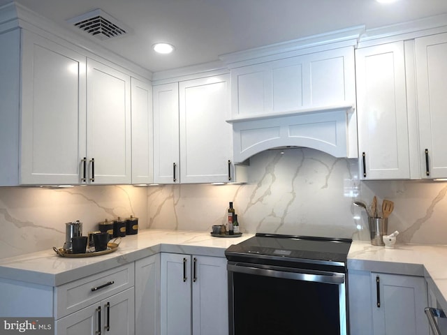 kitchen with white cabinets, backsplash, light stone countertops, and stainless steel range with electric cooktop