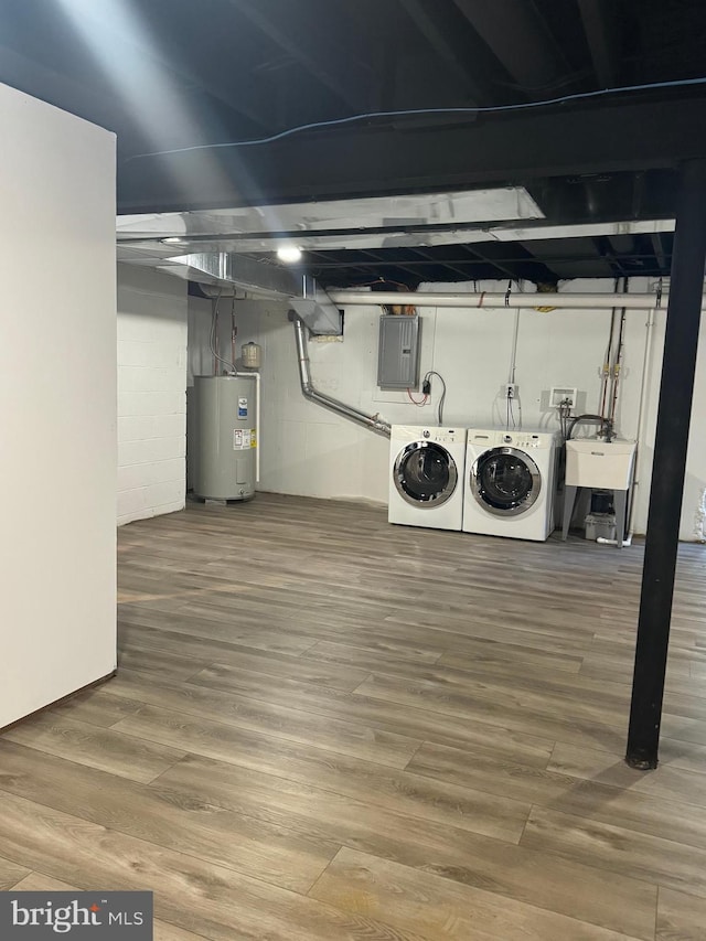 basement featuring sink, electric water heater, electric panel, wood-type flooring, and washer and clothes dryer