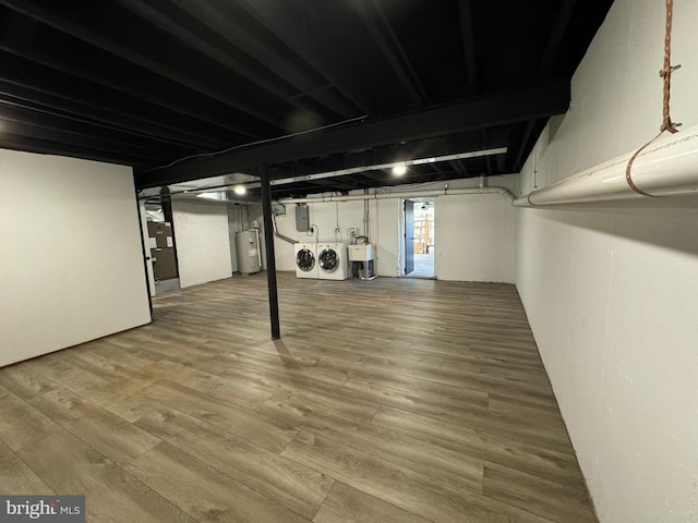 basement with washer and clothes dryer, electric panel, electric water heater, and hardwood / wood-style flooring