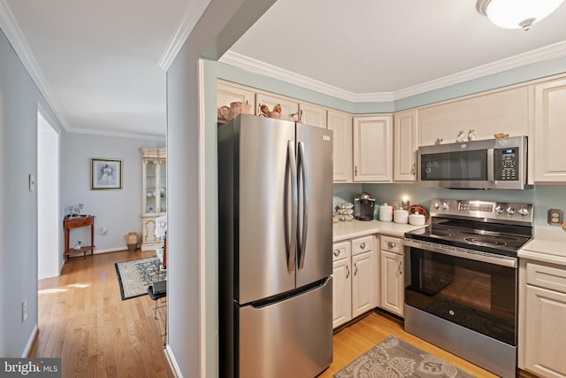 kitchen with ornamental molding, appliances with stainless steel finishes, light hardwood / wood-style flooring, and cream cabinetry