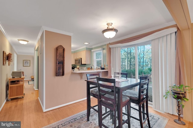 dining room with ornamental molding and light hardwood / wood-style floors