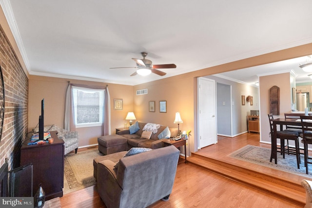 living room with crown molding, brick wall, ceiling fan, and light wood-type flooring