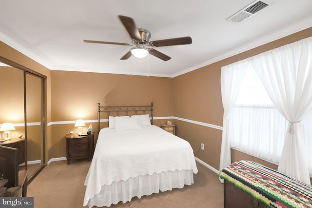 carpeted bedroom featuring crown molding, ceiling fan, and a closet