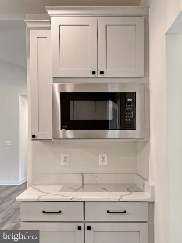 4035 Tamaron Ct, Brandywine, MD 20613 - kitchen featuring stainless steel microwave, light stone counters, white cabinetry, baseboards, and wood finished floors