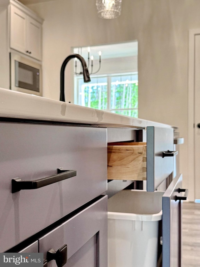 4035 Tamaron Ct, Brandywine, MD 20613 - kitchen with stainless steel microwave, a chandelier, white cabinets, and wood finished floors