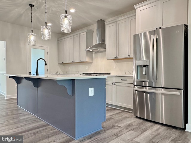 4035 Tamaron Ct, Brandywine, MD 20613 - kitchen with stainless steel refrigerator with ice dispenser, wall chimney range hood, a center island with sink, light wood-type flooring, and a breakfast bar area