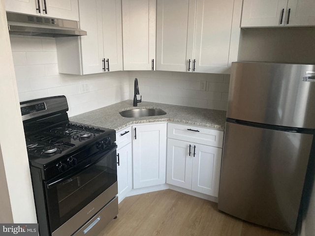 kitchen featuring light stone countertops, range with gas cooktop, sink, white cabinetry, and stainless steel refrigerator