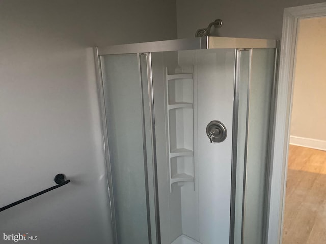 bathroom with hardwood / wood-style floors and a shower with shower door