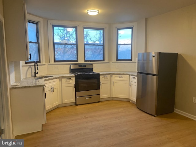 kitchen featuring white cabinetry, plenty of natural light, stainless steel appliances, and light stone counters