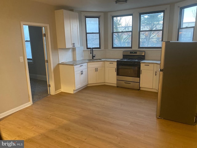 kitchen with stainless steel appliances, white cabinetry, a wealth of natural light, and sink