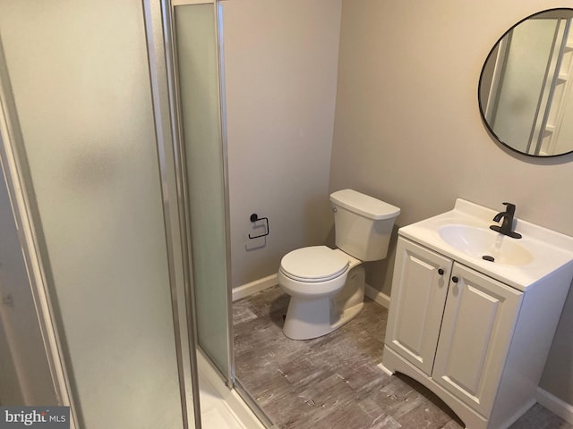 bathroom featuring vanity, hardwood / wood-style flooring, toilet, and a shower with shower door