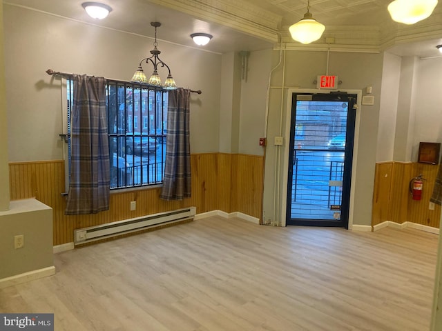 doorway featuring wood-type flooring, baseboard heating, ornamental molding, and wood walls