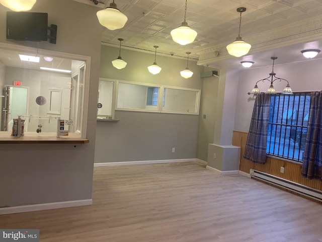 interior space with hardwood / wood-style floors, pendant lighting, and a baseboard heating unit