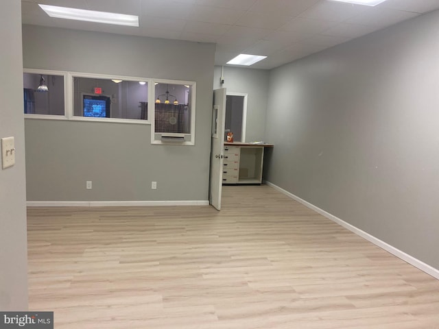 spare room with light hardwood / wood-style flooring and a drop ceiling