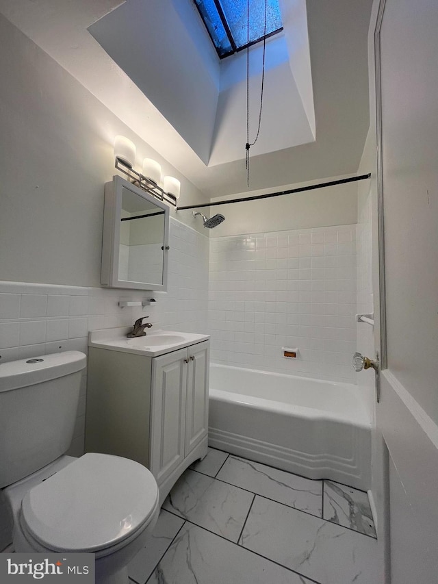 full bathroom with vanity, tiled shower / bath combo, tile walls, and toilet