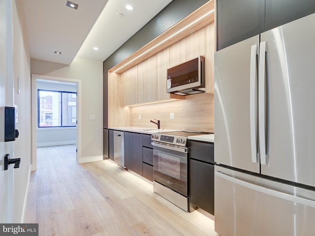 kitchen featuring sink, light brown cabinets, stainless steel appliances, tasteful backsplash, and light hardwood / wood-style flooring