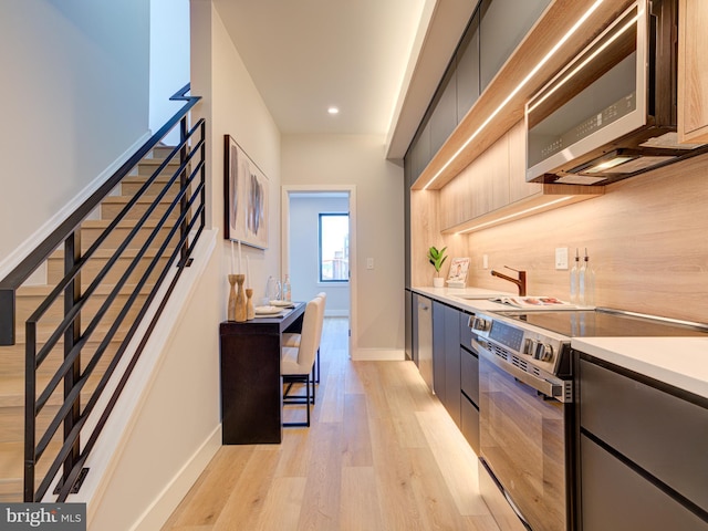 kitchen featuring decorative backsplash, sink, stainless steel appliances, and light hardwood / wood-style floors