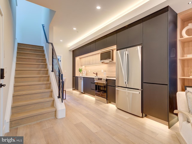 kitchen featuring tasteful backsplash, sink, appliances with stainless steel finishes, and light hardwood / wood-style flooring