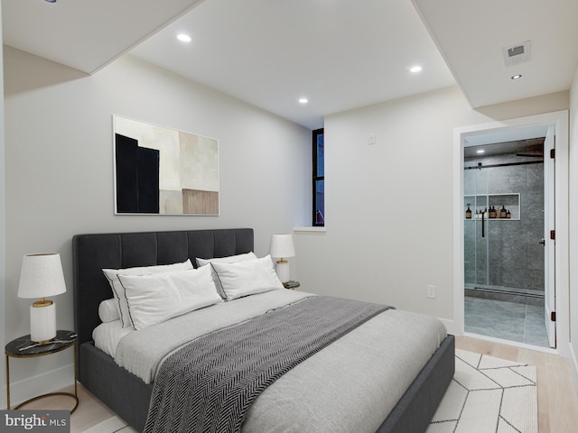 bedroom with connected bathroom and light hardwood / wood-style flooring