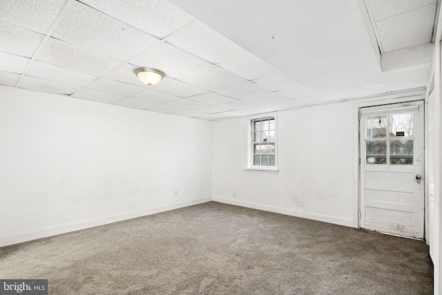 basement featuring a paneled ceiling and dark carpet