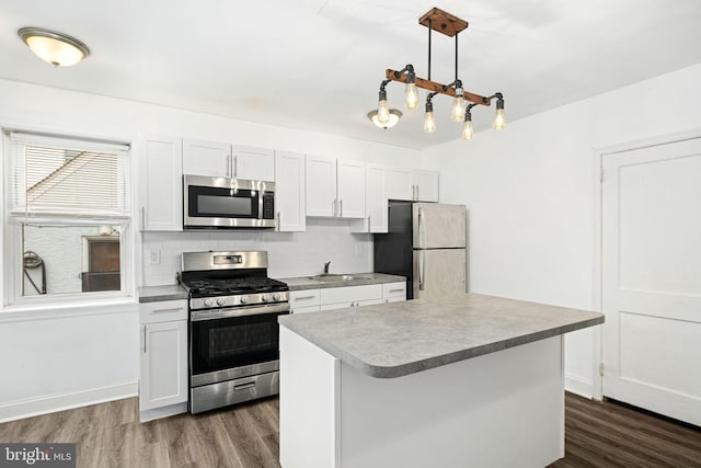 kitchen with pendant lighting, a kitchen island, white cabinetry, stainless steel appliances, and tasteful backsplash