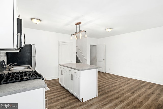 kitchen with pendant lighting, white cabinets, a center island, dark hardwood / wood-style flooring, and sink