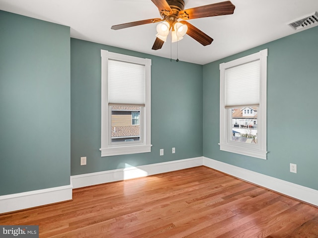 spare room with ceiling fan, a wealth of natural light, and light hardwood / wood-style flooring