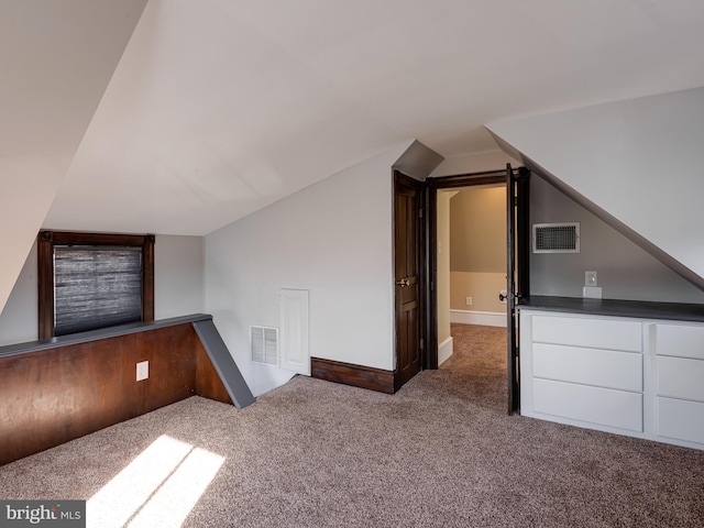 bonus room featuring lofted ceiling and dark colored carpet