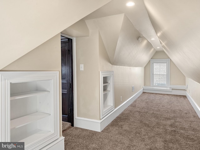 bonus room featuring carpet, built in shelves, and vaulted ceiling