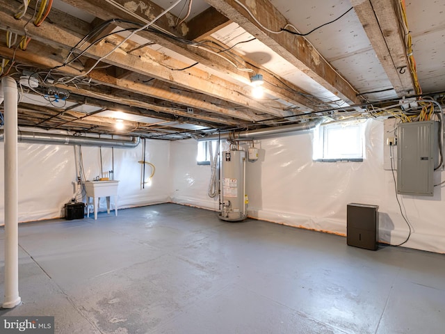 basement featuring electric panel, gas water heater, a healthy amount of sunlight, and sink