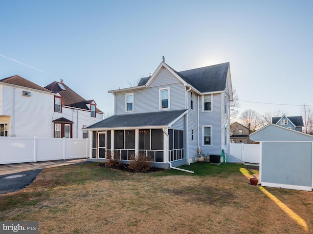 rear view of house with a yard, central AC, a shed, and a sunroom