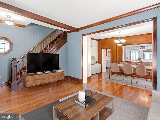 living room with a chandelier, crown molding, wooden walls, and light hardwood / wood-style flooring